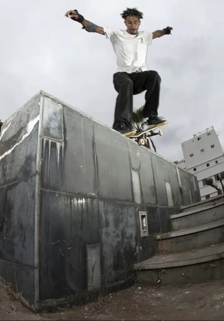 Akram Moundo, founder and coach of Casa Skate Club, balancing on his skateboard along the edge of a high concrete wall