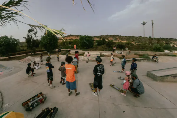 Young skaters gathered in a circle at an outdoor skatepark in the afternoon
