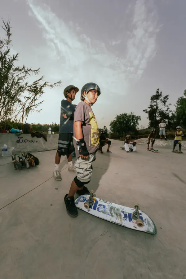 Young skater in a helmet standing beside his board before a session