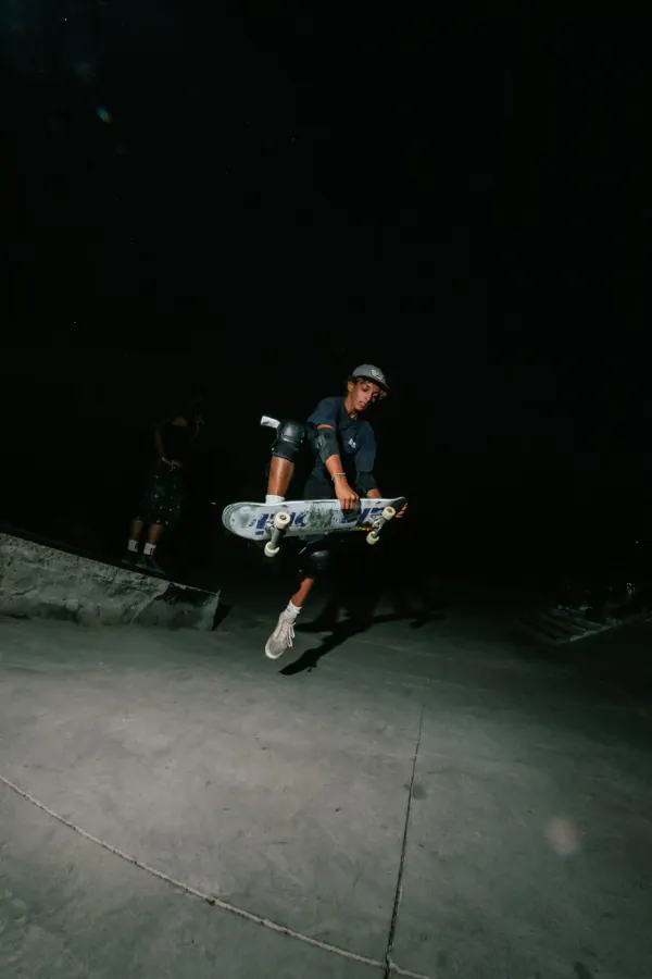 Skater grabbing his board mid-air during a night session