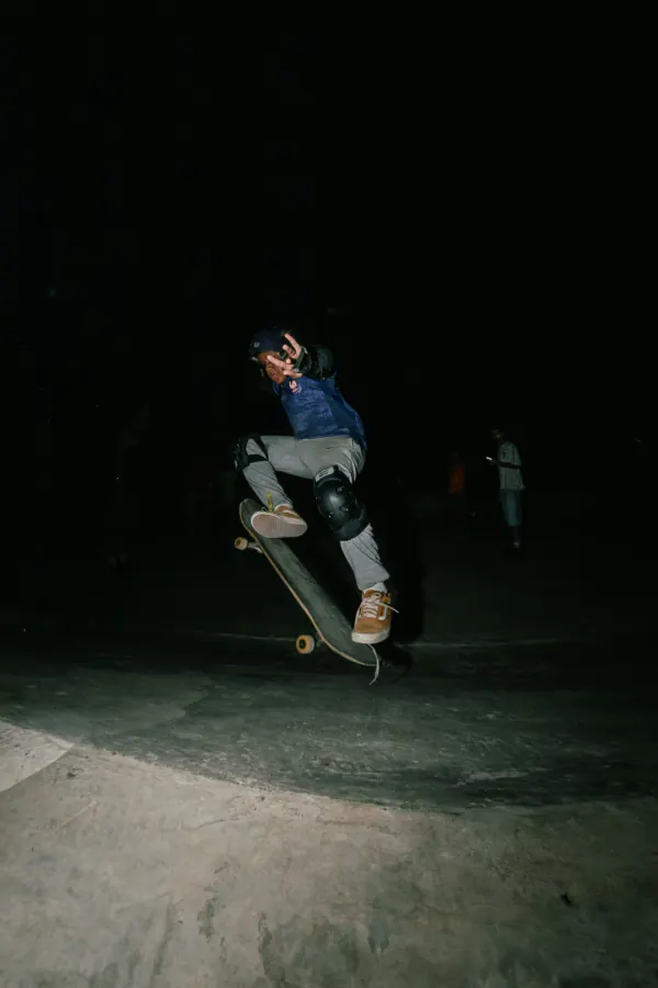 Young skater in a helmet landing an ollie at night