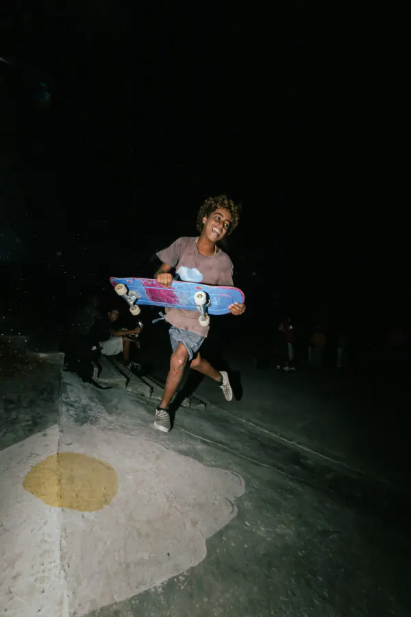 Laughing skater running with his board under the flash