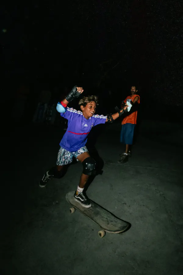 Kid in a purple jersey pushing off on his board with arms raised