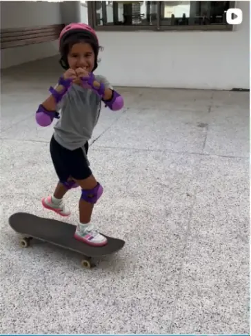 Young skater in a pink helmet and pads standing on a skateboard